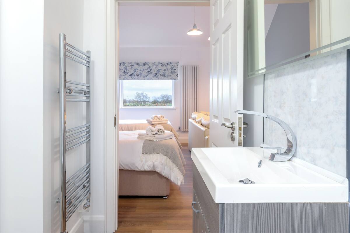 A modern bathroom with a white sink, a mirror, and a towel rack.