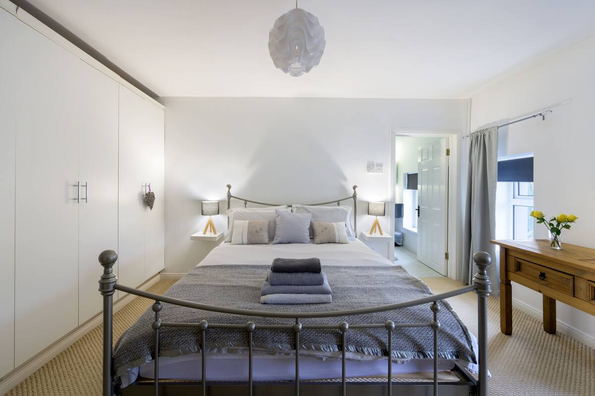 A bedroom with a bed, bedside tables, a wooden dresser, and a mirror.
