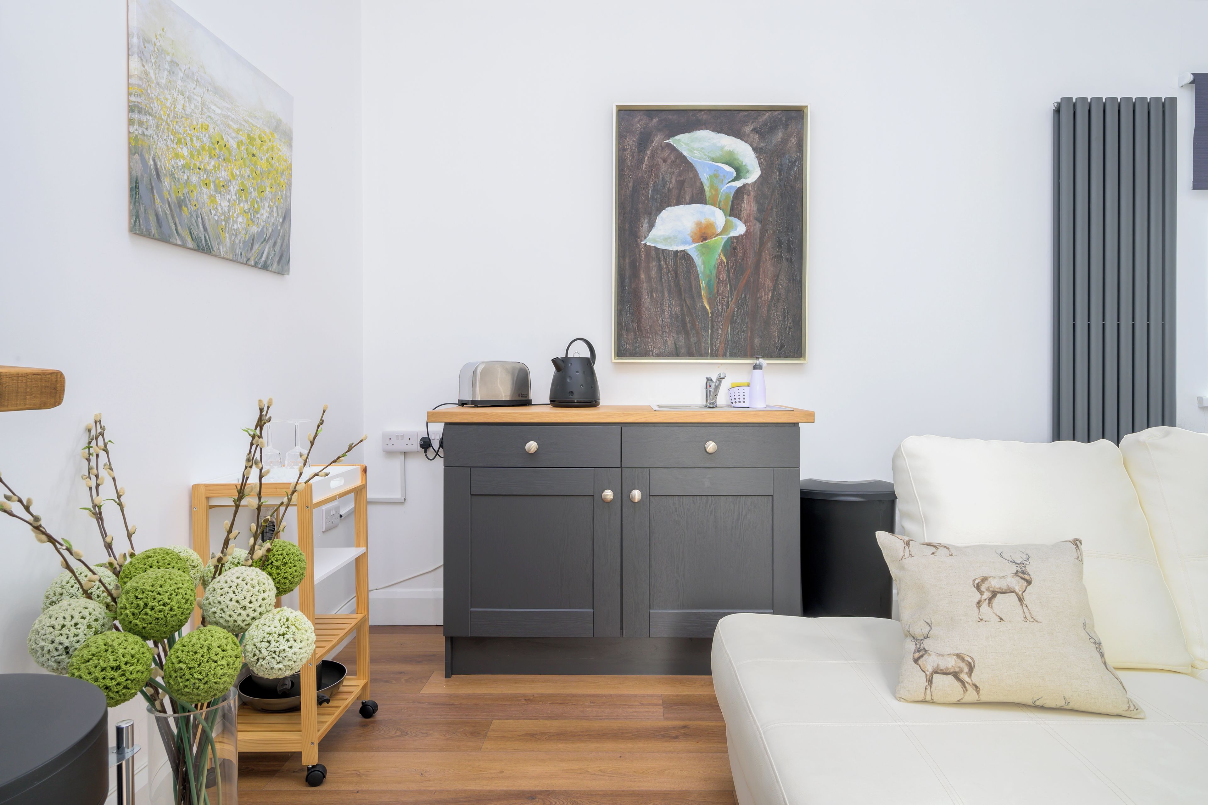 A modern living room with a grey cabinet, a white sofa, and a wooden side table.