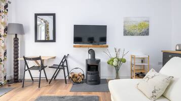 Uma sala de estar moderna com um sofá, uma TV, uma lareira e um espaço de jantar com cadeiras.