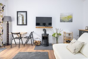 Una sala de estar moderna con sofá, televisor, chimenea y un comedor con sillas.