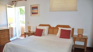 A neatly made bed with a wooden headboard, two bedside tables with lamps, a wooden dresser, and a door leading outside. - Stylish and well-equipped, private pool, close to amenities, free AC & Wifi (Vilamoura)