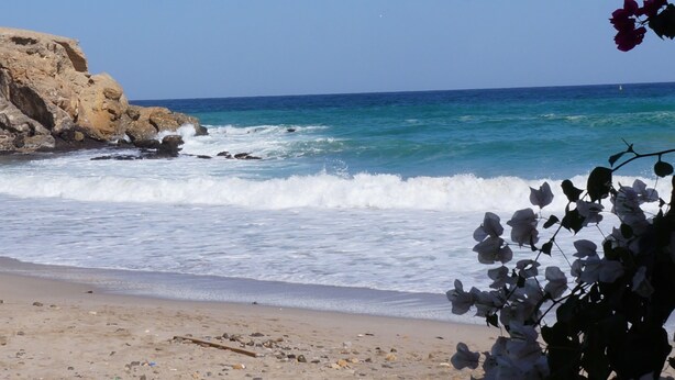 Una playa con acantilados rocosos y olas.