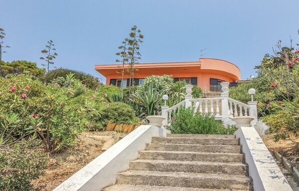 A curved building with a staircase leading to a white railing.