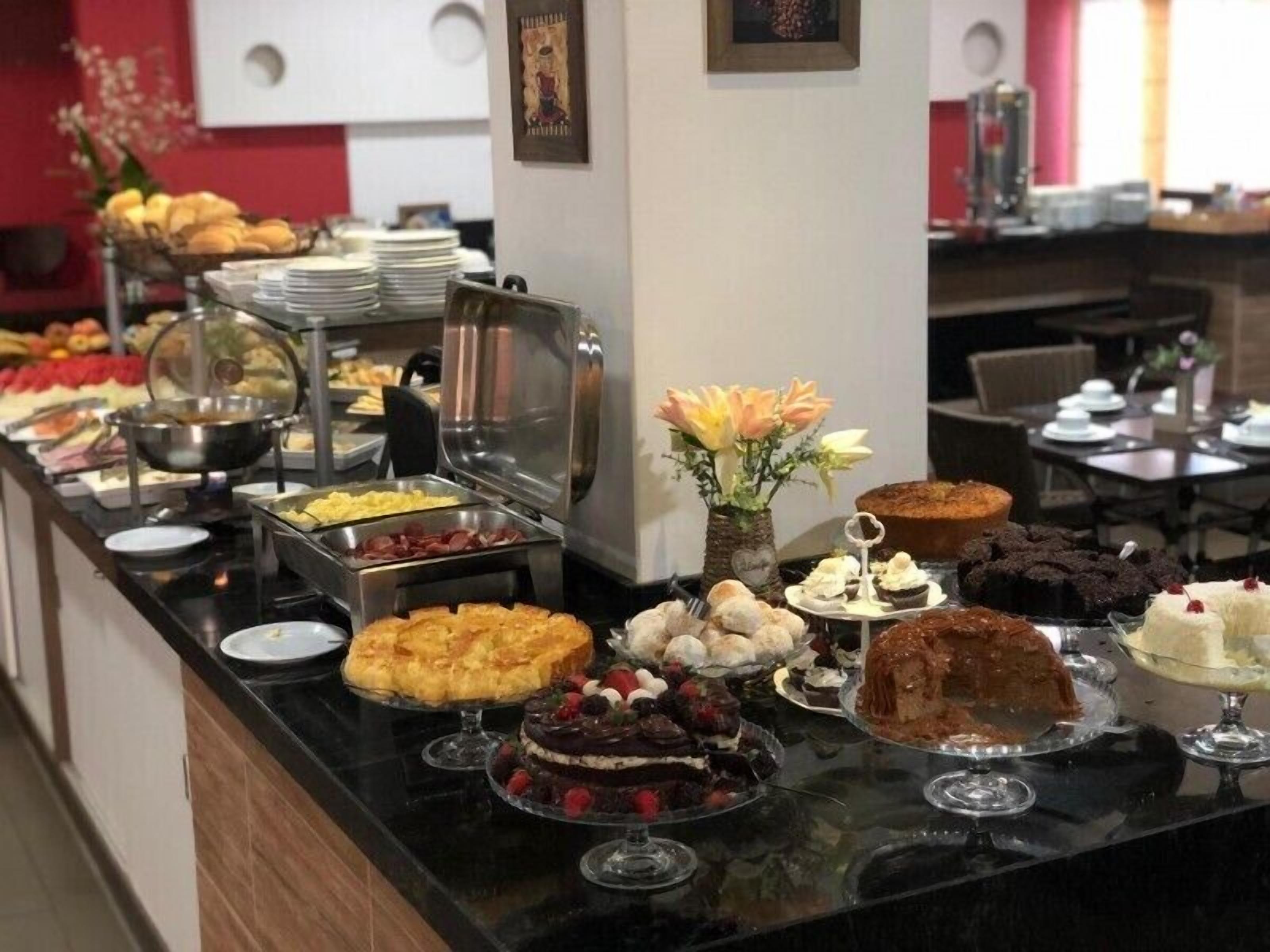 A buffet with various dishes and desserts, including cakes and pastries, arranged on a counter.