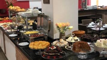 A buffet with various dishes and desserts, including cakes and pastries, arranged on a counter.