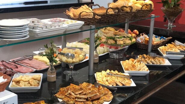 A buffet with various food items including bread, pastries, and salads. - Dallas Hotel (Palotina)