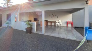 A building with a brick fireplace, a small dining area with a table and chairs, and a blue trash bin. - Dallas Hotel (Palotina)