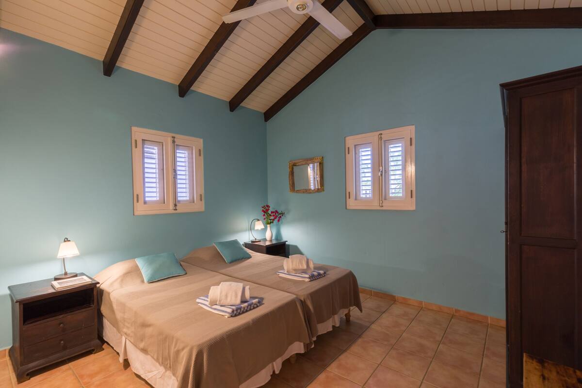Un dormitorio con dos camas, una mesita de noche, una lámpara y un ventilador de techo.