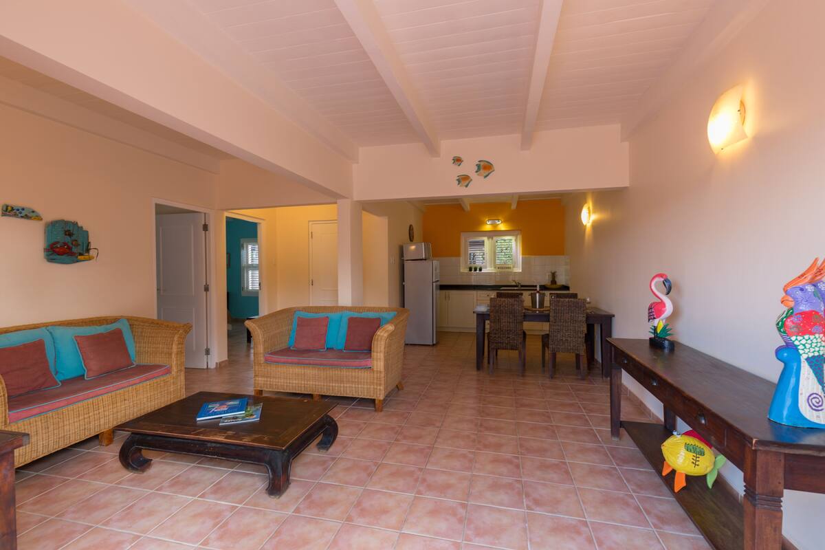 Una sala de estar con muebles de mimbre, una mesa de centro y un comedor con mesa y sillas.