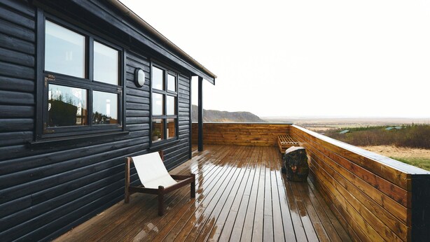 Um deck de madeira com um banco e vista para a paisagem.