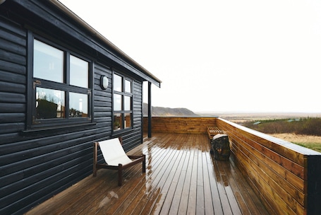 A wooden deck with a bench and a view of the landscape.