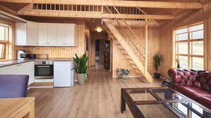 Um interior espaçoso de madeira com cozinha, sala de jantar e escada que leva a um andar superior.