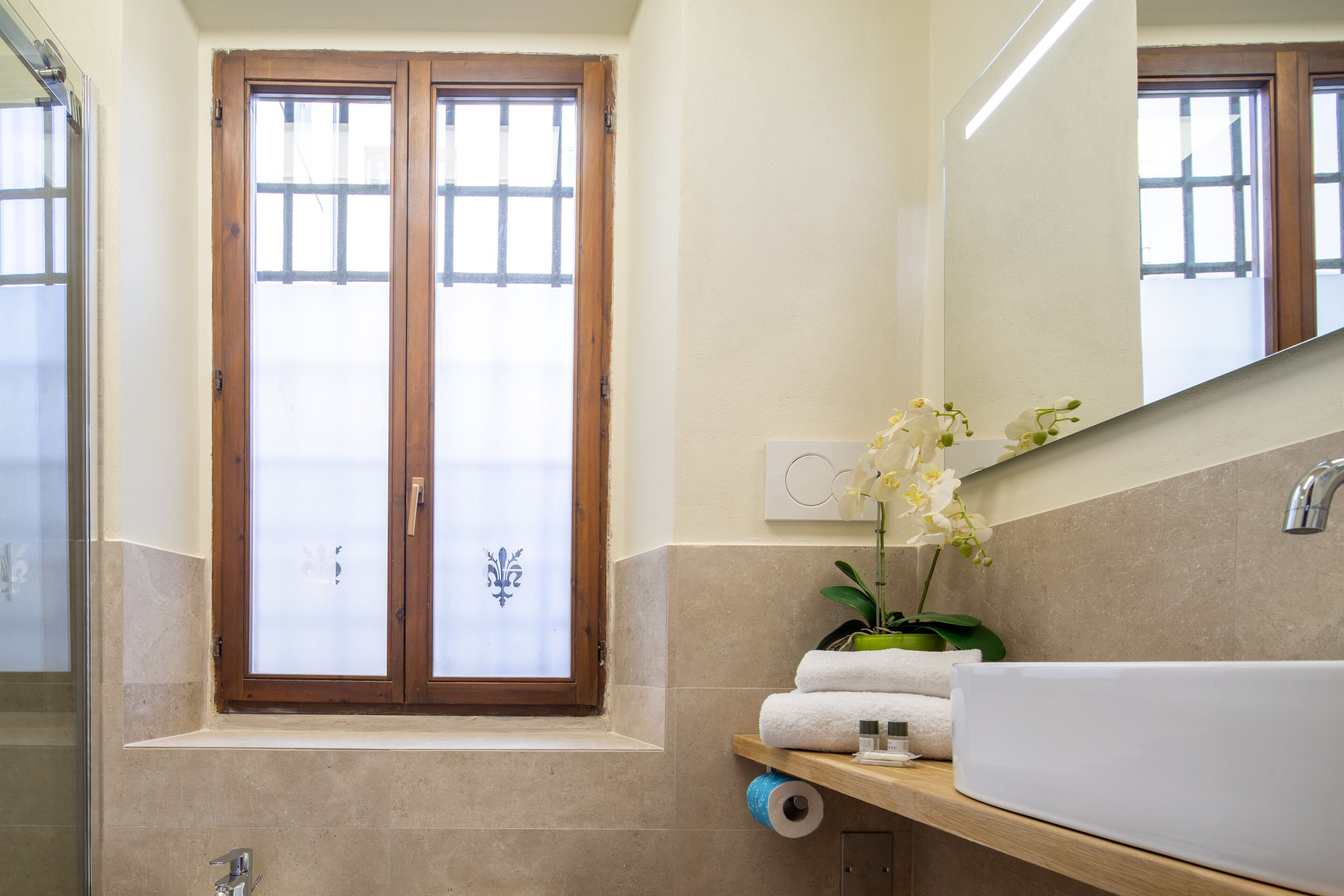 A bathroom with a large window, a sink, and a mirror.