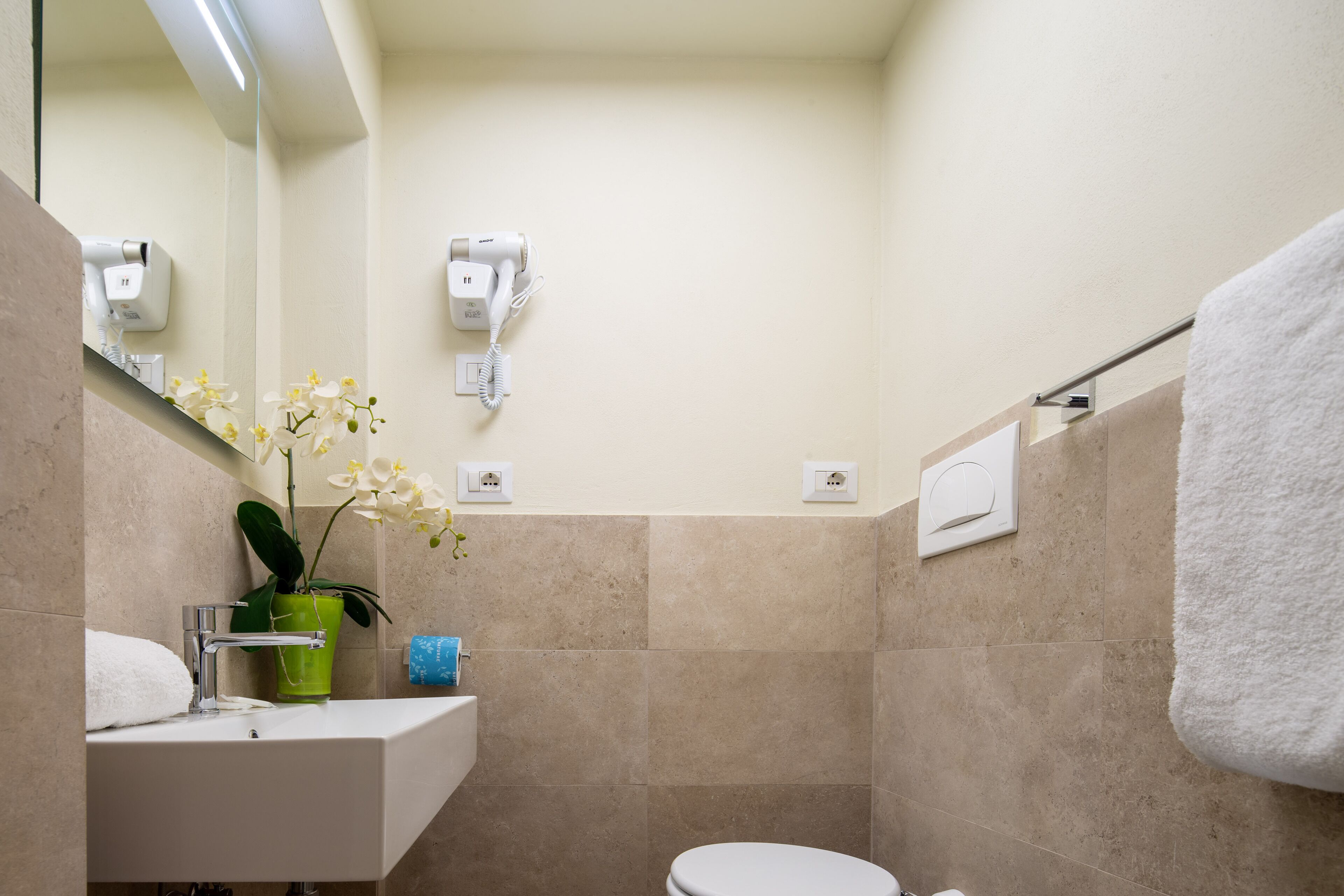 A bathroom with a sink, mirror, hair dryer, and towel rack.