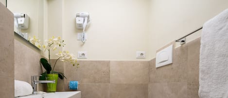 A bathroom with a sink, mirror, hair dryer, and towel rack.