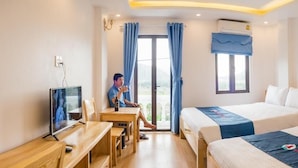 A hotel room with a desk, two beds, a TV, and a window with curtains. - Cat Ba White Pearl (Hai Phong)
