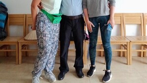 Three people standing in a room with wooden benches and a blackboard on the wall. - Cat Ba White Pearl (Hai Phong)