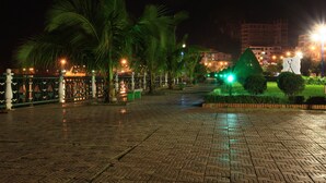 A nighttime outdoor area with a paved walkway, palm trees, and a green-lit pyramid structure. - Cat Ba White Pearl (Hai Phong)