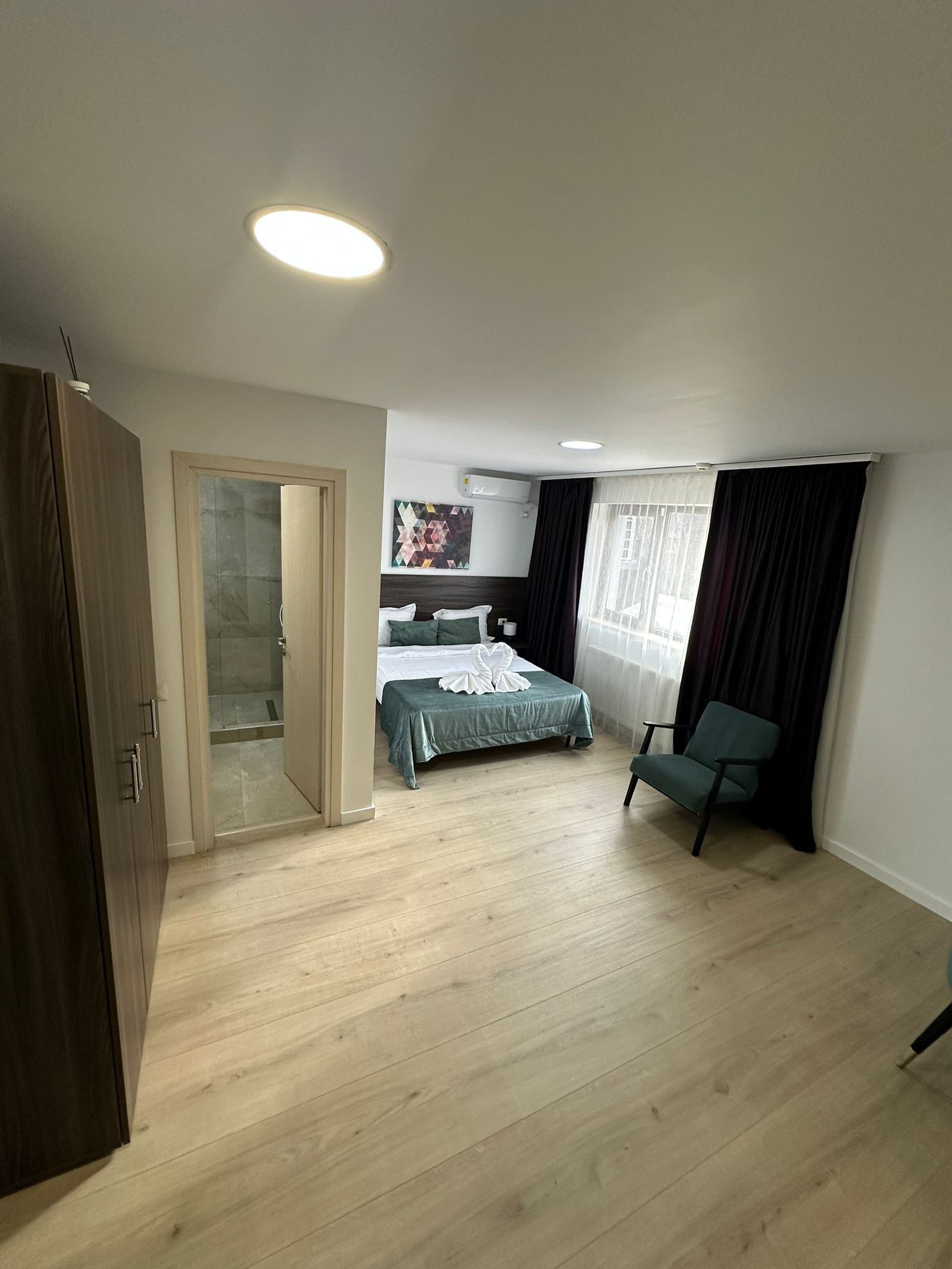 A hotel room with a bed, a chair, a wardrobe, and a bathroom door.