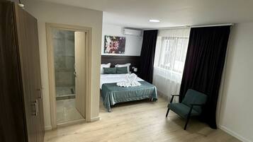A hotel room with a bed, a chair, a wardrobe, and a bathroom door.