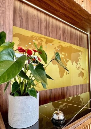 A wooden wall with a world map, a potted plant with green leaves and red flowers, and a black object on a reflective surface. - Bliss Inn Tunari (Tunari)