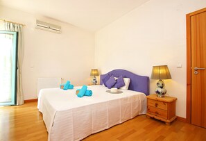 A bedroom with a bed, two bedside tables, a nightstand, a window with curtains, and a door.