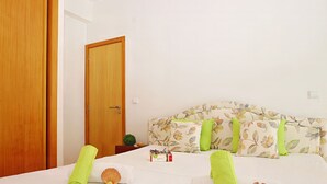 Een hotelkamer met een bed, een houten deur, een nachtkastje en een kleine plant in pot.