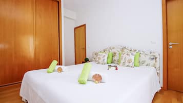 A hotel room with a bed, wooden doors, a floral headboard, and a small nightstand with a lamp.
