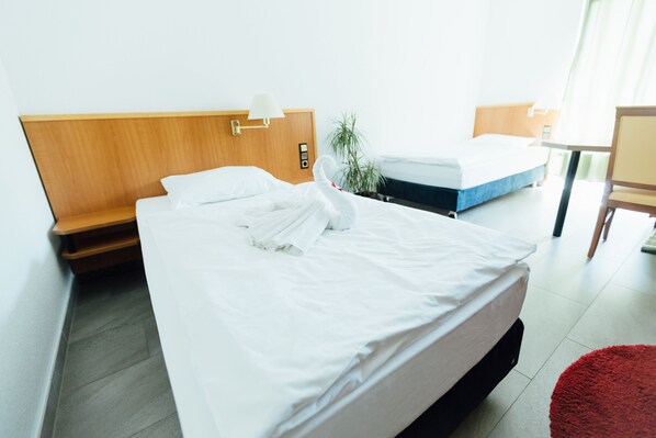 A hotel room with a bed, bedside table, lamp, and a small potted plant. - Heilbronner Pension am Theater (Heilbronn)