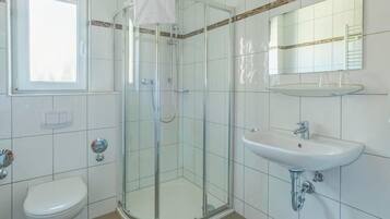 Une salle de bain avec une douche à parois de verre, un lavabo blanc et des toilettes.