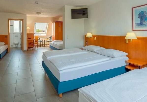 A hotel room with a large bed, a desk, and a chair. There is a TV mounted on the wall and a window providing natural light. - Heilbronner Pension am Theater (Heilbronn)