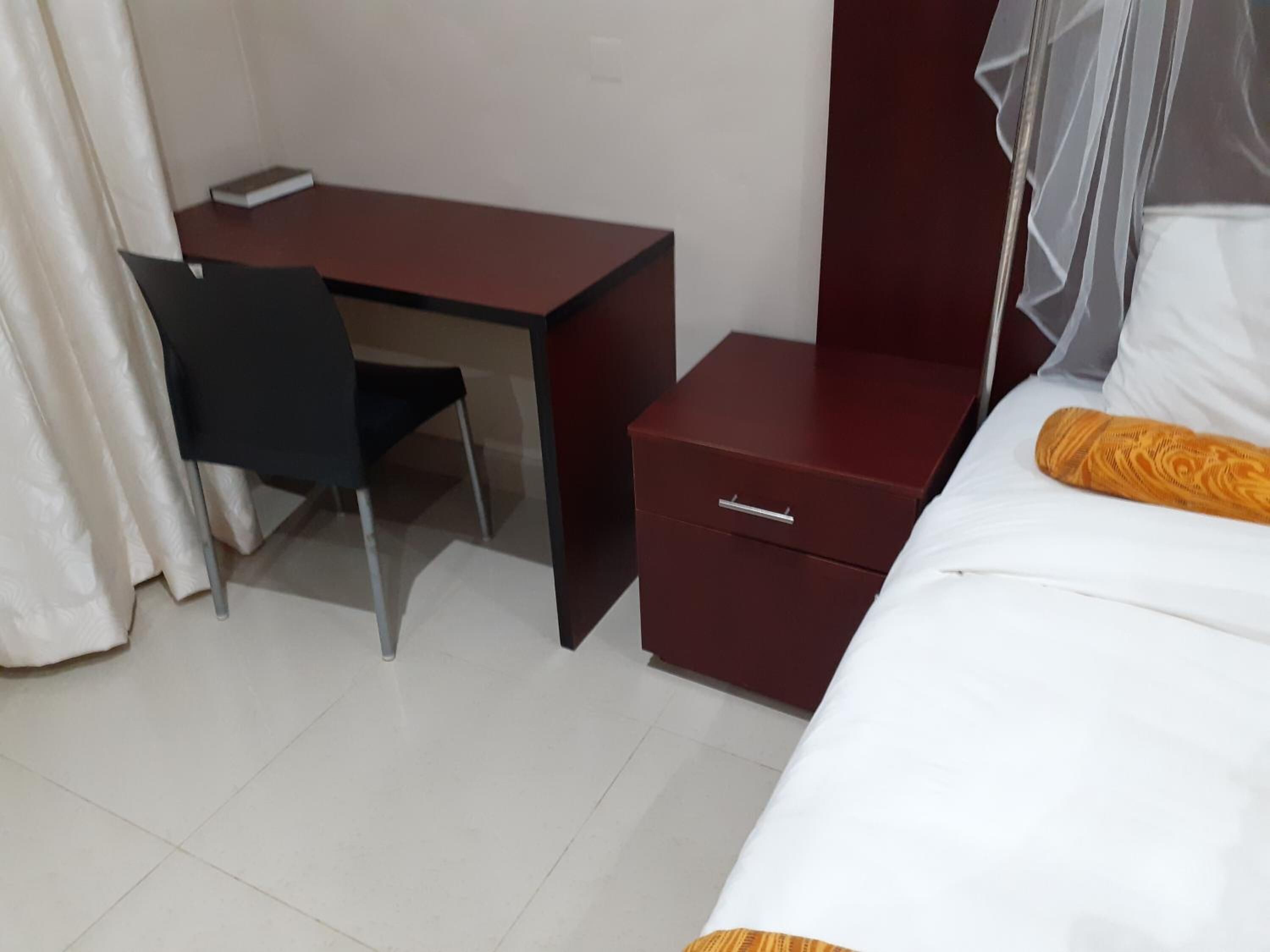 Una camera d'albergo con un letto, una scrivania, una sedia e un comodino.