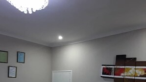 A living room with two dark brown sofas, a white door, and a ceiling light fixture. - Delight Lodge (Blantyre)