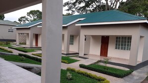 A row of modern buildings with green roofs and a well-maintained garden area with neatly trimmed hedges and pathways. - Delight Lodge (Blantyre)