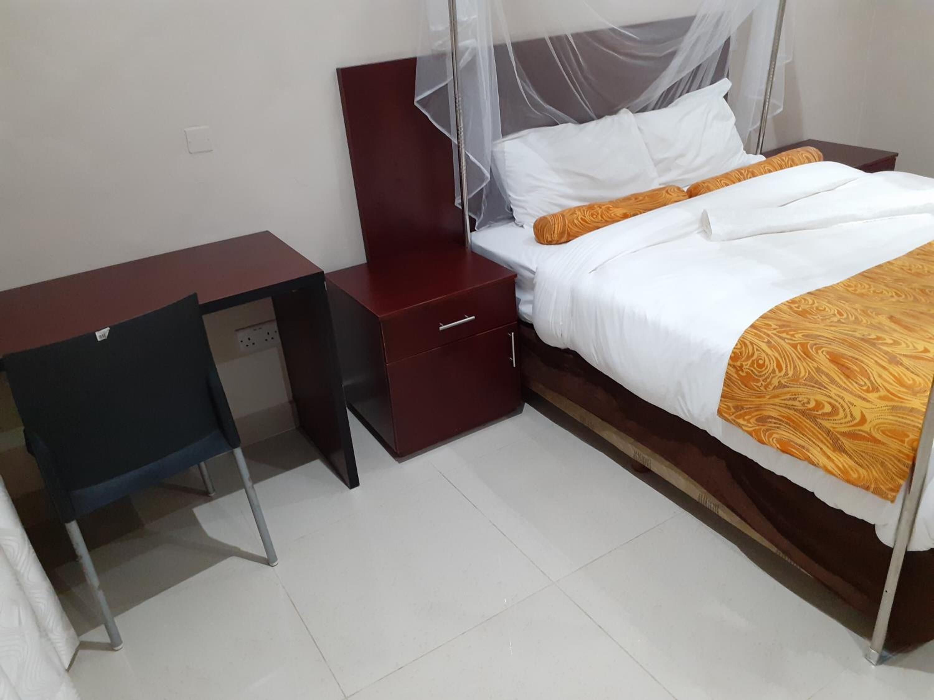 Een slaapkamer met een bed, een bureau en een nachtkastje.