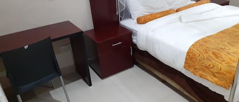 Een slaapkamer met een bed, een bureau en een nachtkastje.