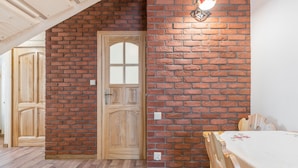 Una habitación con puerta de madera, pared de ladrillo y una mesa con mantel floral.