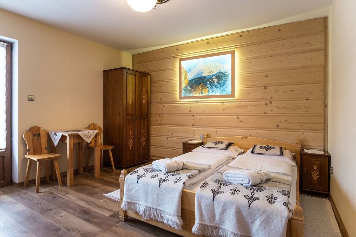 A cozy bedroom with a wooden headboard bed, a desk with a chair, and a wardrobe.