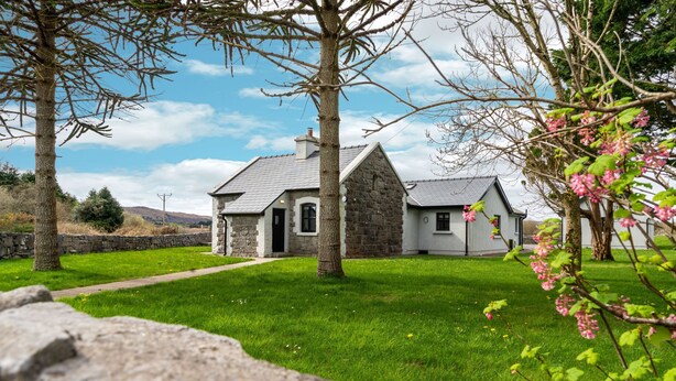A stone house with a grassy yard and a stone wall in the foreground. - Cottage 345 - Oughterard  - sleeps 10 guests  in 4 bedrooms (Oughterard)