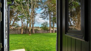A view through an open door into a grassy yard with trees and a stone wall. - Cottage 345 - Oughterard  - sleeps 10 guests  in 4 bedrooms (Oughterard)