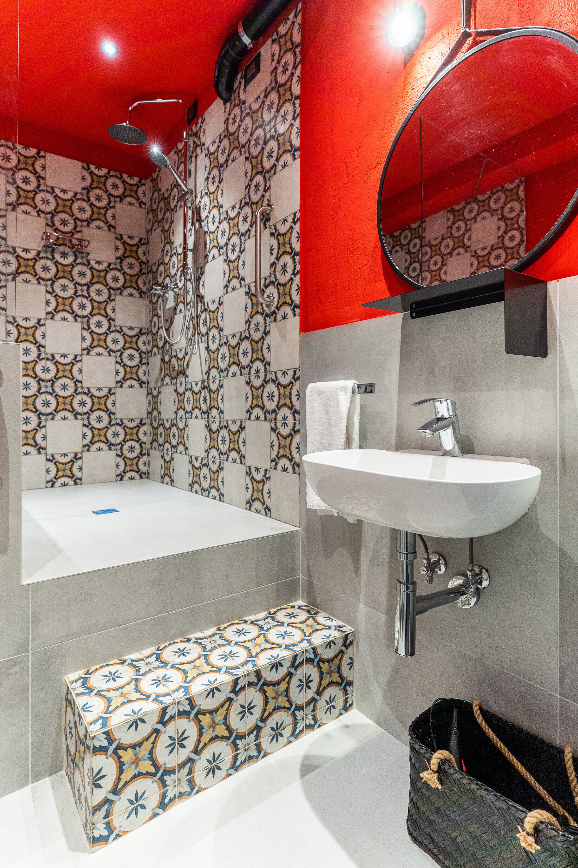 A bathroom with a patterned tile wall, a white sink, a mirror, and a bathtub.