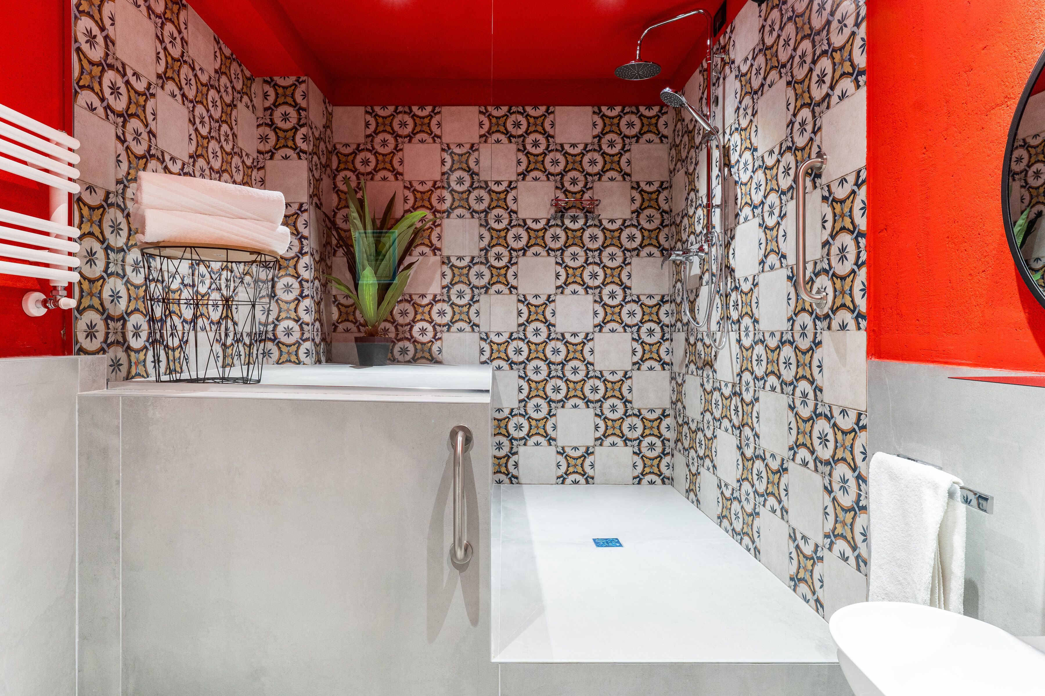 A bathroom with a tiled shower wall, a white sink, and a red accent wall.