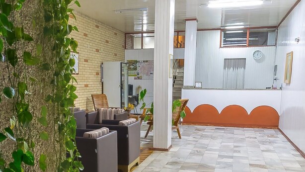A hotel lobby with a brick wall, a reception desk, and a staircase. - Hotel Jóia (Cascavel)