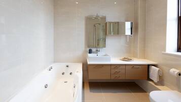 A modern bathroom with a bathtub, sink, mirror, and toilet.