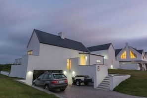 A modern two-story house with a garage, a driveway, and a well-lit exterior.