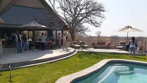 Un espace piscine à bords incurvés, une pelouse verdoyante et un coin salon extérieur agrémenté de parasols.