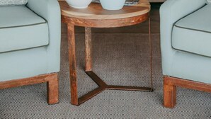 Une pièce confortable avec un lit, une petite table ornée d’une plante et d’un saladier de fruits, et deux fauteuils.