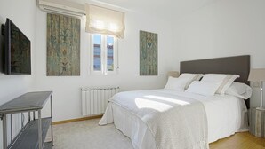 A bedroom with a bed, a radiator, a window with a curtain, and a wall-mounted TV. - Beautifuly Decorated 2 Bd Apart With Private Terrace, Reina Sofia (Madrid)