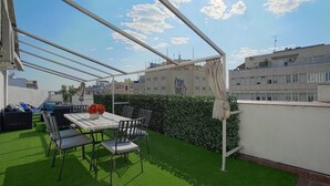 A rooftop terrace with artificial grass, a table with chairs, and a view of surrounding buildings. - Beautifuly Decorated 2 Bd Apart With Private Terrace, Reina Sofia (Madrid)